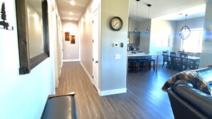 A modern living room with a dark brown leather sofa, a wooden bench, and a dining area with a chandelier. - *** Double MASTER Cabin *** Walk to Lake and Golf Course (Williams)