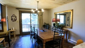 A dining area with a wooden table and chairs, a chandelier, and a large mirror on the wall. - Epic Mountain Views! 2 Miles North of Purgatory! Heated Pool ! (Durango)