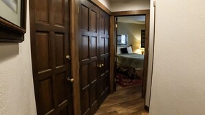 A hallway with a wooden door leading to a bedroom with a bed and a nightstand. - Epic Mountain Views! 2 Miles North of Purgatory! Heated Pool ! (Durango)