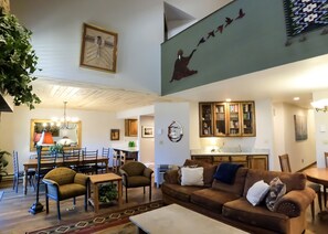 A spacious living area with a dining table, sofas, and a kitchen in the background.