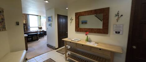 A hallway with a wooden bench, a mirror, and a vase with a flower.