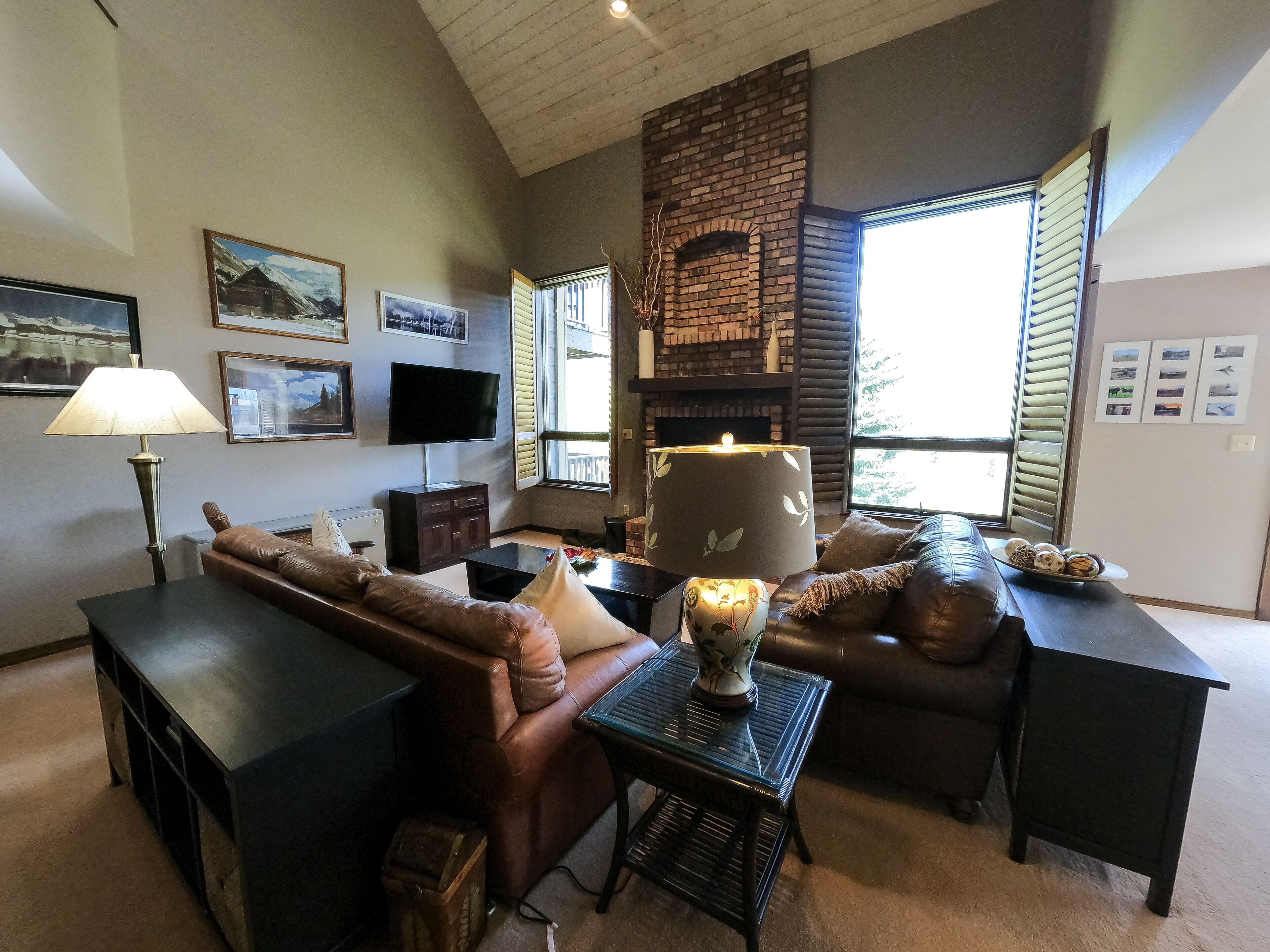 Ein Wohnzimmer mit Ledersofa, Couchtisch, Fernseher und Kamin.