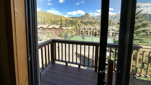 Eine Holzterrasse mit Blick auf ein Resort, einschließlich Gebäude und Berge.