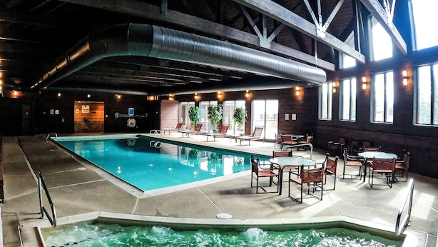 Ein Innenpool mit Whirlpool, Liegestühlen und Tischen.