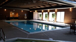 Une piscine intérieure avec un revêtement intérieur en bois, un poste de surveillance pour le sauveteur et un panneau indiquant la zone de la piscine.