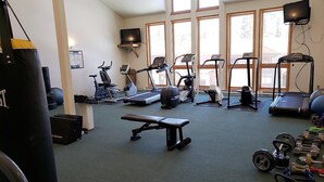 Une salle de sport équipée de divers appareils d’exercice, notamment des tapis de course, des vélos d’appartement et des poids libres.