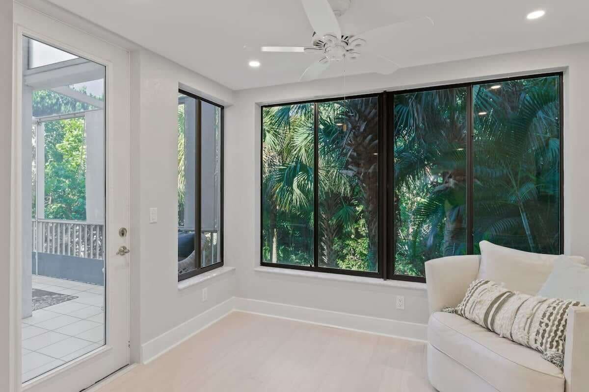 A room with large windows, a ceiling fan, and a white couch.