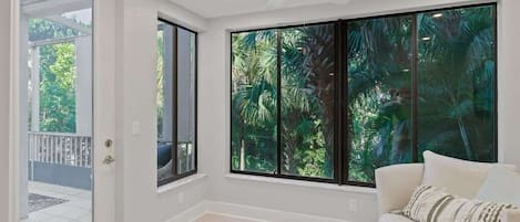 A room with large windows, a ceiling fan, and a white couch.