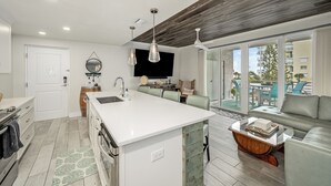 A modern kitchen with a central island, white cabinetry, and pendant lighting. - Turtle Beach Beachview Condo - Beautifully updated - Private - Quiet Ocean View (Cocoa Beach)