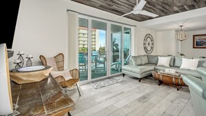 A spacious living room with a large sectional sofa, a wooden coffee table, and a dining area with wicker chairs. - Turtle Beach Beachview Condo - Beautifully updated - Private - Quiet Ocean View (Cocoa Beach)