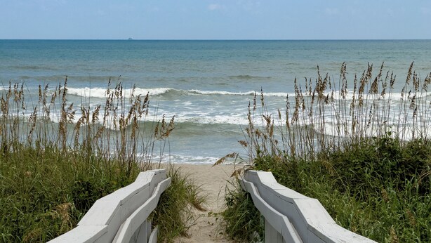 A wooden boardwalk leading to a beach with waves and seaweed. - Turtle Beach Beachview Condo - Beautifully updated - Private - Quiet Ocean View (Cocoa Beach)