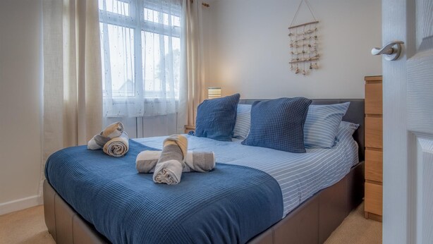 A neatly made bed with blue bedding and rolled towels, a bedside lamp, and a wall decor piece.