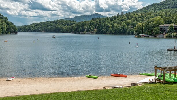 A lakeside view with kayaks and a beach.