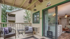 A covered porch with outdoor seating, a sliding glass door leading to a kitchen, and a sign for paddle on canoe rentals.