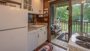 A kitchen with white cabinets, a sink, and a stove. There is a sign above the door that reads "BEING TOGETHER".