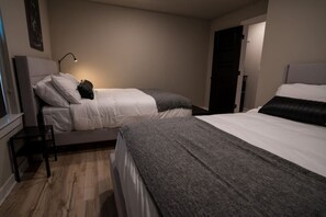 A bedroom with two beds, a bedside table, a lamp, and a door. - The Bike Inn #1, Devils Den Double Suite (Bentonville)