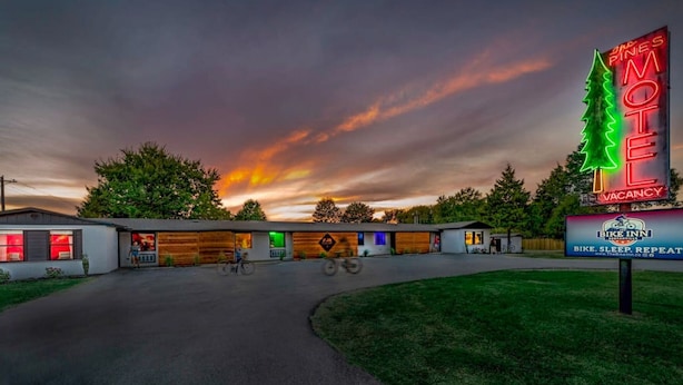Ein Motel mit leuchtendem Neonzeichen, einem Bereich für Fahrradstellplätze und einem Sonnenuntergang im Hintergrund.