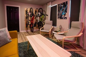 A room with a wooden door, a wall-mounted bike rack, two armchairs, a small table, and a window with a view of a mountain. - The Bike Inn #1, Devils Den Double Suite (Bentonville)