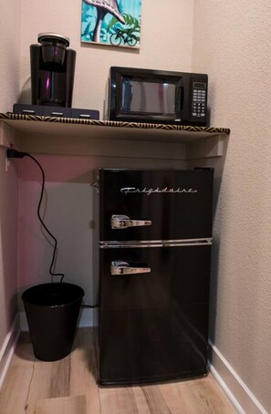 A black refrigerator with a freezer compartment and a microwave on top. - The Bike Inn #1, Devils Den Double Suite (Bentonville)
