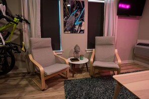 A room with two chairs, a small table, a bicycle, and a wall-mounted TV.