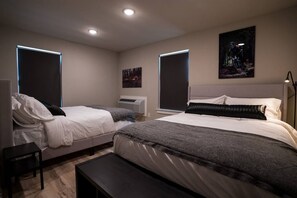 Un dormitorio moderno con dos camas, un banco y obras de arte en las paredes.