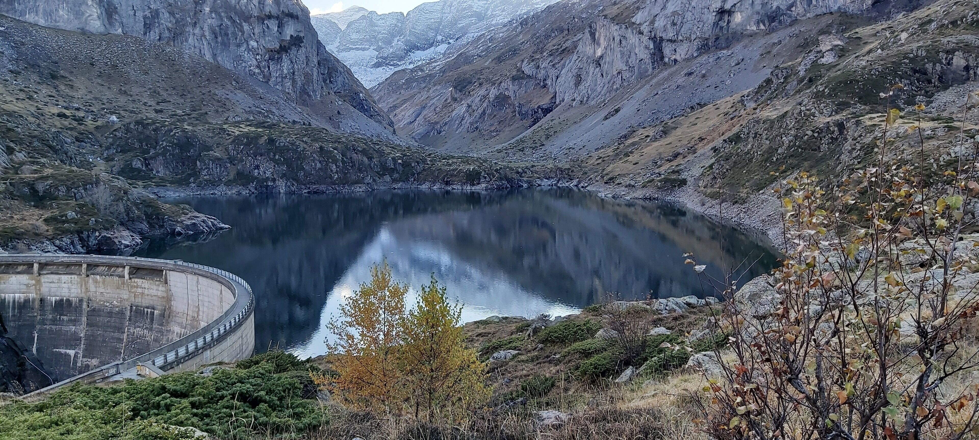 Eine Berglandschaft mit einem See, einem Staudamm und spärlicher Vegetation.