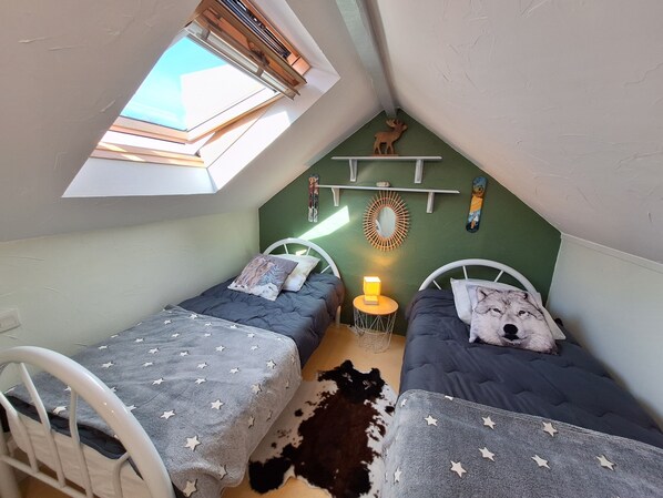 Une petite pièce agréable et chaleureuse, avec deux lits, une lucarne, un miroir fixé au mur et une petite table avec une lampe.