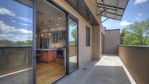 A modern kitchen with a large island, sliding glass doors to a balcony, and a view of the outdoors. - Downtown Penthouse Condo (Durango)