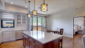 A modern kitchen with a central island, pendant lights, and a view to the outside. - Downtown Penthouse Condo (Durango)