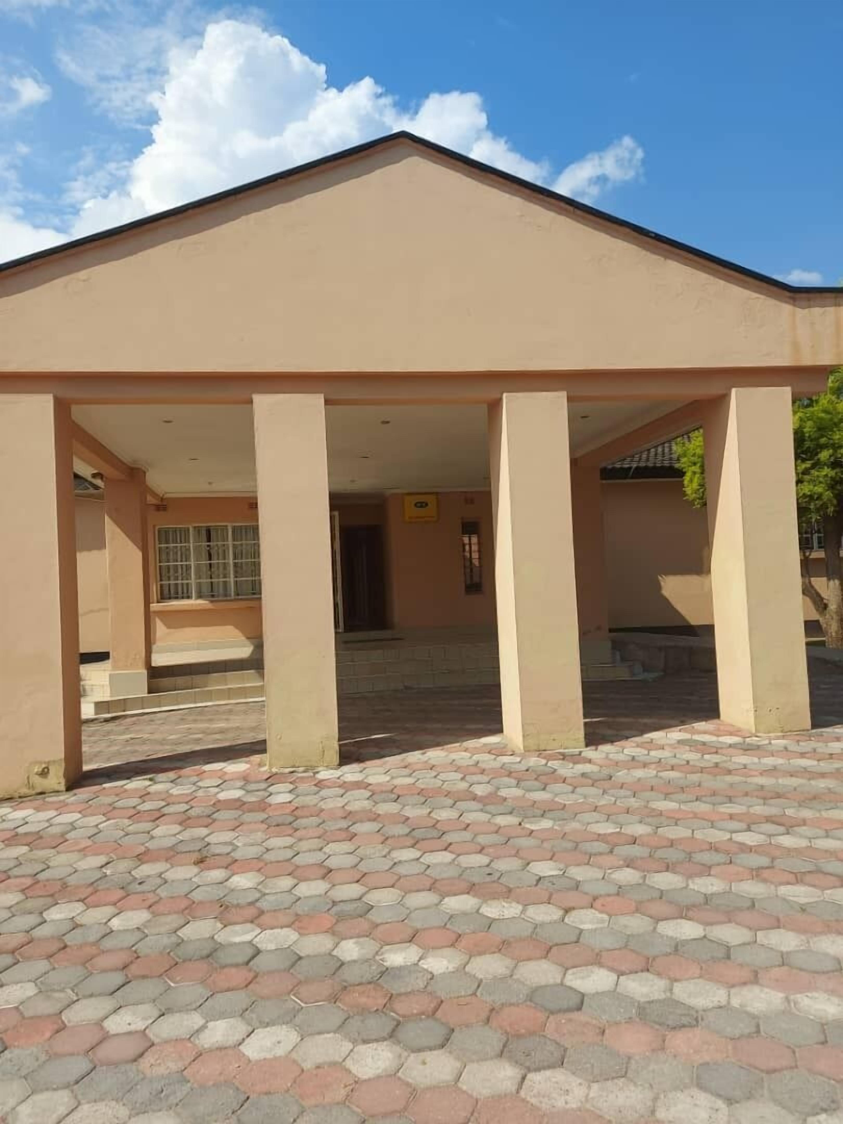 A building with a covered entrance, hexagonal tile flooring, and a clear sky.