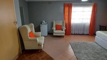 A room with a sofa, two armchairs, a small table, and a cabinet.