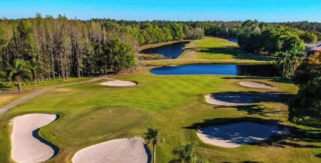 Golfkenttä, jossa on hiekkabunkkereita, vesiesteitä ja metsäinen alue.