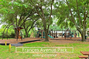 Explore Frances Avenue Park's playground surrounded by lush greenery and mature trees, perfect for leisurely walks and family activities.
