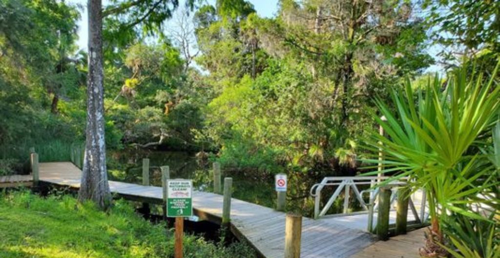Un cadre naturel avec un pont en bois et un panneau indiquant la réserve naturelle James E. Grey, accessible en 5 minutes en voiture.