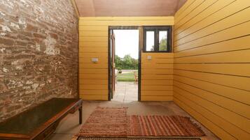 A hallway with yellow walls, a wooden bench, and a rug.