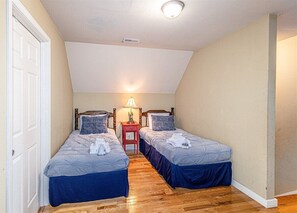 Cozy bedroom with two single beds, a bedside table, and a sloped ceiling.