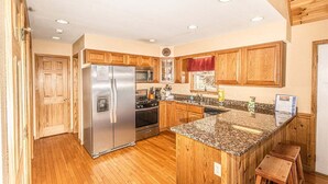 Una cocina con armarios de madera, un refrigerador de acero inoxidable, un microondas y una encimera de granito.