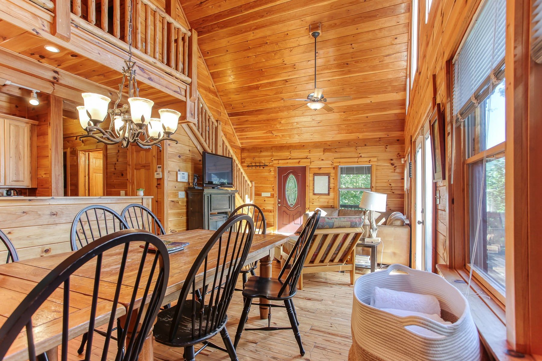 Interior d'una cabana de fusta amb zona de dinar, cuina i grans finestres.