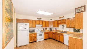 A kitchen with wooden cabinets, a refrigerator, stove, microwave, and a sink.