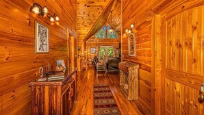 A wooden interior with a central hallway, wooden walls, a chandelier, and a window with a view. - Shooting Star Ridge: Mountain View Cabin Near Cherokee with Hot Tub (Whittier)