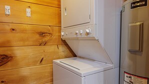 Una lavadora y secadora compactas frente a un panel de pared de madera.