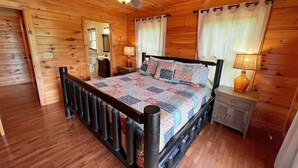 Une chambre aux murs lambrés, avec un lit, des tables de chevet et un ventilateur de plafond.