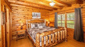 Une chambre située dans un chalet en rondins, avec un lit en bois, une table de chevet, une lampe et une fenêtre avec des rideaux.