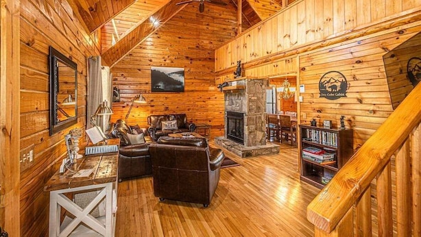 L’intérieur d’un chalet confortable, avec une cheminée, des fauteuils en cuir et une bibliothèque.
