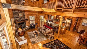 Un intérieur spacieux de chalet en bois avec une cheminée en pierre, un coin repas et un espace salon confortable.