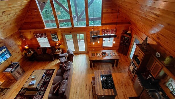 A cozy cabin interior with a wooden interior, a sofa, a dining table, a kitchen area, and large windows. - 'Sunrise in the Smokies' - Where Mornings Begin Best (Bryson City)