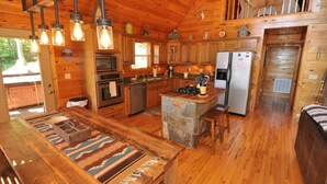 A wooden cabin interior with a kitchen, dining area, and a stone island. - 'Sunrise in the Smokies' - Where Mornings Begin Best (Bryson City)