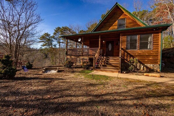 A log cabin with a porch, a staircase, and a small front yard.
