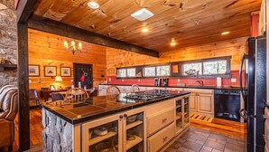 Eine großzügige Küche mit einer großen Kochinsel, Holzschränken und einer Wand mit Steinverkleidung.