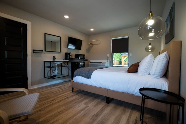 Quarto moderno com uma cama grande, uma escrivaninha, uma cadeira e uma televisão.